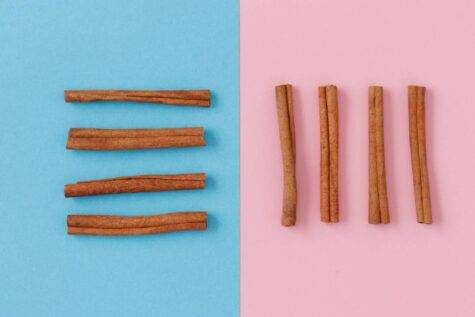 parallel angeordnete Zimtstangen vor rosa und blauem Hintergrund