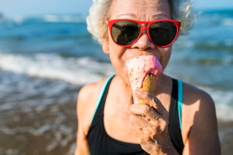 Ältere Frau schleckt Eiscreme am Strand.