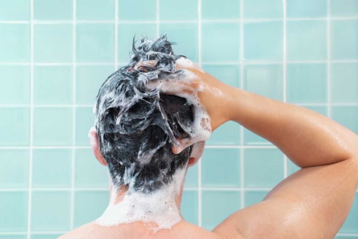 Mann, der sich die Haare wäscht, Ansicht von hinten
